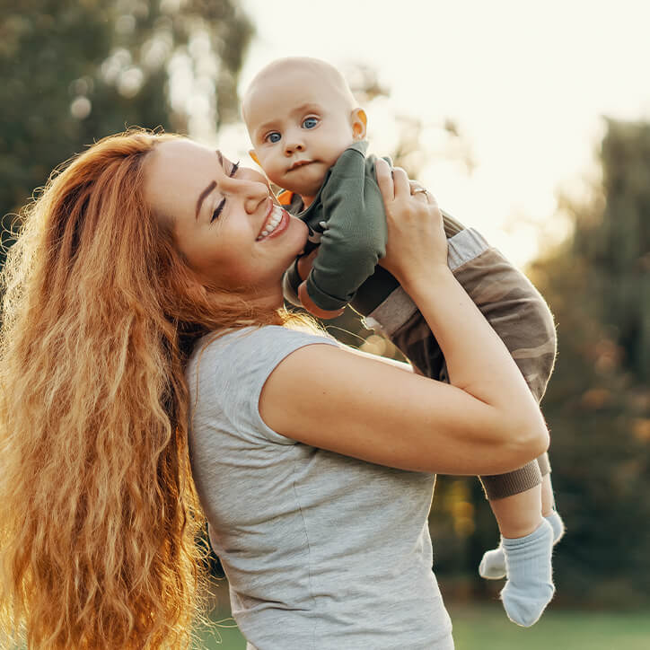 Frau ohne Haarausfall hebt Baby hoch